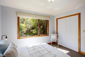a bedroom with a large bed and a window at Peninsula Paradise in Dunedin