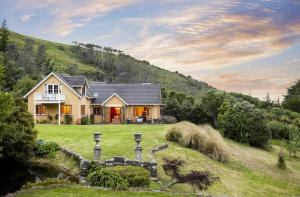 a house on a hill with a grass yard at Peninsula Paradise in Dunedin