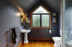 a bathroom with a window and a sink and a toilet at Peninsula Paradise in Dunedin