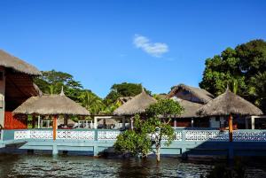 a restaurant with straw umbrellas next to a body of water at Marionel Hôtel in Ampilahoa