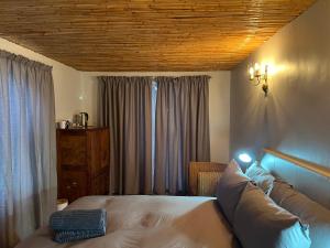 a bedroom with a bed with a couch and curtains at The Old Posthouse in Ladismith +18 photos