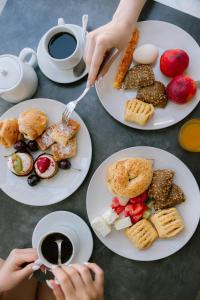 a table with plates of food and a person with a cup of coffee at Aliston Hotel Thassos in Skala Potamias