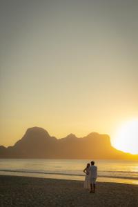 Ein Paar steht bei Sonnenuntergang am Strand. in der Unterkunft Lio Lio Suites Private Pools in El Nido