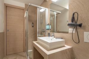a bathroom with a white sink and a shower at Molveno Garden Suite in Molveno +28 photos