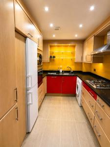 a kitchen with red cabinets and a white refrigerator at Spacious 3BR Lancaster Gate Near Hyde Park in London