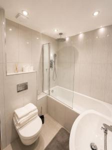 a bathroom with a toilet and a tub and a sink at Spacious 3BR Lancaster Gate Near Hyde Park in London