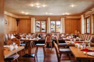 a restaurant with wooden tables and chairs and windows at Gästehaus Walserheimat in Riezlern