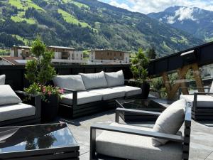 a patio with couches and tables on a balcony with mountains at rocking home in Aschau