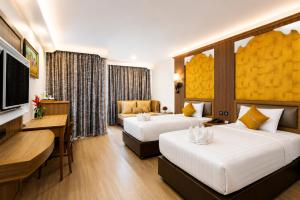 a hotel room with two beds and a television at Aiyara Palace in North Pattaya