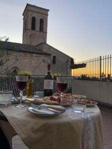 a table with a bottle of wine and wine glasses at App. con terrazza panoramica in centro-Montefalco in Montefalco
