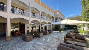 a hotel with chairs and umbrellas in a courtyard at Benitses Arches Hotel in Benitses