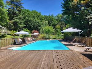 a swimming pool with chairs and umbrellas on a wooden deck at Domaine de Bagnegrole in Saint-Cyprien