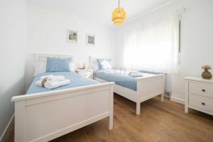 a white bedroom with two beds and a window at Los Sauces By Silastur in Villaviciosa