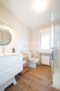 a bathroom with a sink and a toilet and a mirror at Los Sauces By Silastur in Villaviciosa