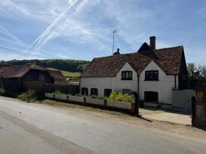 an old white house with a fence next to a street at Cottage in the Hambleden Valley in Henley on Thames