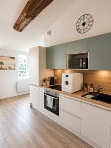 a kitchen with white cabinets and a clock on the wall at Escapade cosy - Sauternes & Château à pied in Villandraut
