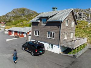 a woman walking in front of a house at ROOMS by Kåkern Bridge in Sund
