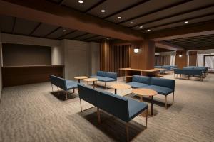 a waiting room with blue chairs and tables at 西伊豆 巡り in Ukusu