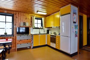 a kitchen with yellow cabinets and a white refrigerator at Holiday Home Långberget in Sysslebäck