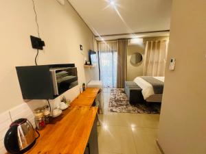 a living room with a television and a bedroom at Falaza Lodge Jozini in Bhokweni