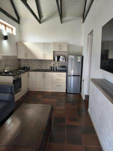 a kitchen with white cabinets and a stainless steel refrigerator at The Museum Cottage in Sabie