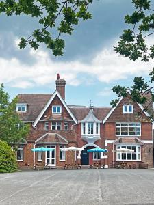 a large red brick building with blue umbrellas in front at The Hickstead Hotel By Uno-FREE PARKING in Bolney