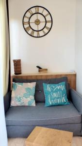 a clock on the wall above a couch with pillows at Apartment with a large tree-lined terrace in Sanary-sur-Mer