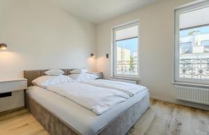 a white bedroom with a large bed and a window at Słoneczne Tarasy in Rewal