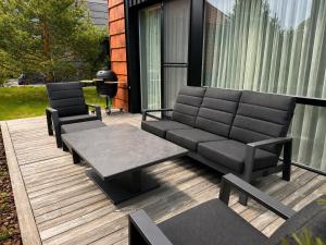 a patio with two chairs and a couch on a deck at Sakalo kopa in Palanga