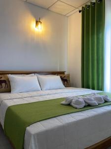 a bedroom with a large bed with green curtains at Mahagedara Villa Wilpattu in Nochchiyagama