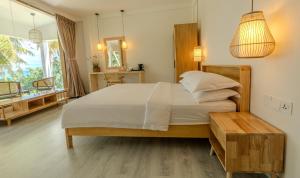 ein Schlafzimmer mit einem großen Bett und einem Tisch in der Unterkunft Odi Beachfront Kamadhoo in Kamadhoo