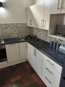 a kitchen with white cabinets and a black counter top at The Museum Cottage in Sabie