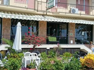 a patio with an umbrella and chairs and plants at HOTEL GIORDANA in Loano