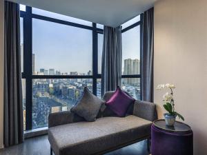a living room with a couch in front of a large window at Mercure Chengdu Downtown Hotel in Chengdu