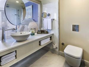 ein Badezimmer mit Waschbecken, Toilette und Spiegel in der Unterkunft Rixos Downtown Antalya - The Land Of Legends Access in Antalya