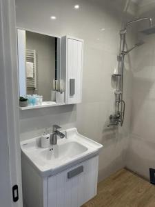 a white bathroom with a sink and a mirror at terrace kaprovan in Urekis Sadguri +11 photos