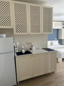 a kitchen with white cabinets and a sink and a bed at terrace kaprovan in Urekis Sadguri