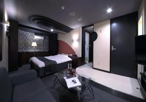 a bedroom with a bed and a living room with a couch at HOTEL K's L Adult only in Urigōchō
