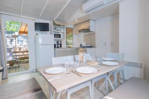 a kitchen with a wooden table with white plates on it at Camping Le Parc in Saint-Paul-en-Forêt