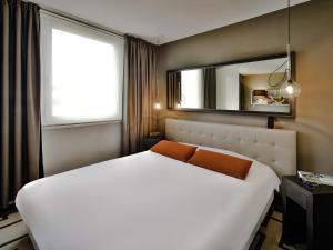 a bedroom with a large white bed and a mirror at Adagio Grenoble Centre in Grenoble