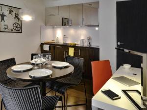 a dining room with a table and chairs and a kitchen at Adagio Grenoble Centre in Grenoble