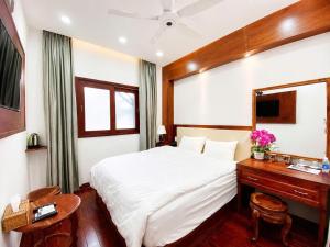 a bedroom with a white bed and a desk and a bed sidx sidx at Pandora Hotel Cần Thơ in Can Tho +29 photos