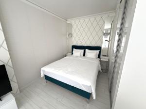 a small bedroom with a bed with white sheets and pillows at Cloé Apartman by Noir Hotel in Szeged