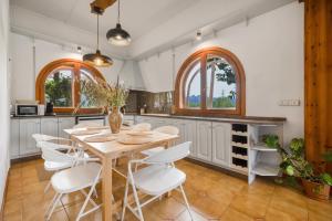 a kitchen with a wooden table and white chairs at Ca la Crish in Horta de San Joan