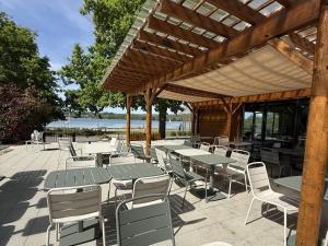 a patio with tables and chairs and a wooden pergola at Camping maeva Escapades Domaine de la Vingeanne in Longeau
