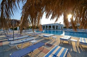 a group of lounge chairs next to a swimming pool at Nikos 2 Studios & Apartments in Kardamaina