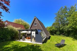 a small house in a field with two chairs at Ferienhaus Windspiel in Neuharlingersiel
