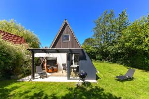 a small house with a pitched roof on a lawn at Ferienhaus Windspiel in Neuharlingersiel +54 photos