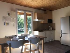 a kitchen with a table and chairs and a refrigerator at Camping maeva Escapades Domaine de la Vingeanne in Longeau