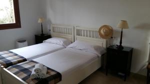 two beds in a bedroom with white sheets at Sa Talaia in Lluc